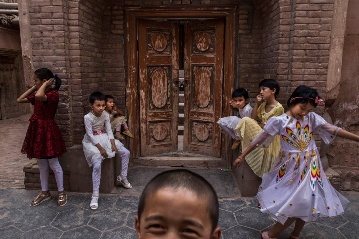 Uiguriske barn sitter utenfor en låst moske som ble stengt av myndighetene, i Kashgars gamleby. Foto: Foto: Kevin Frayer/Getty Images